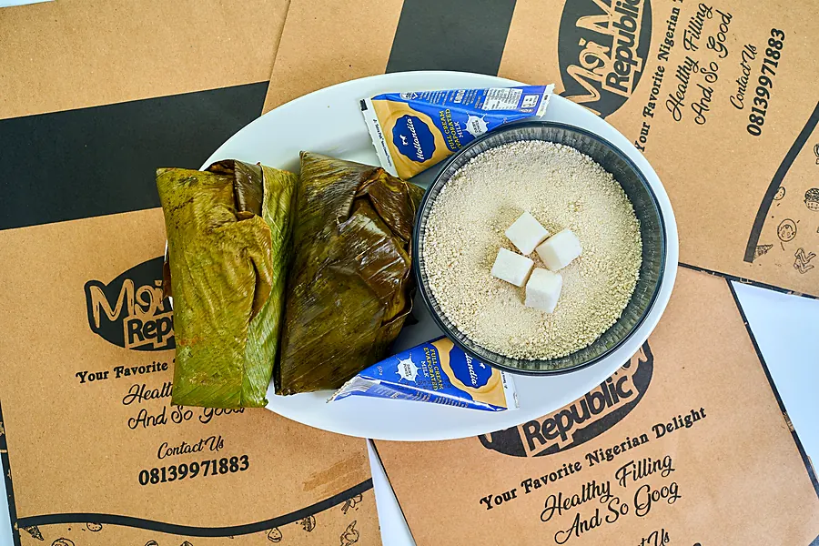 Leaf-wrapped moi moi with garri and milk on Moi Moi Republic bags